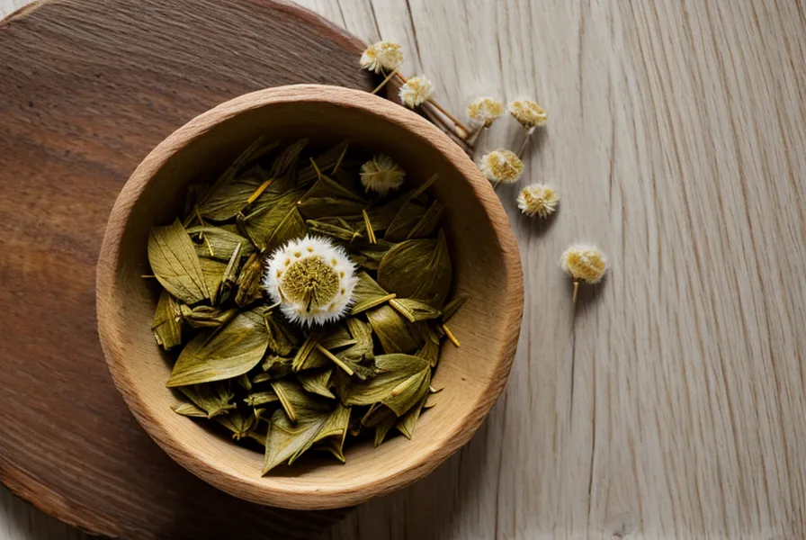 Dried dandelion leaves in a wooden bowl next to a tea cup.